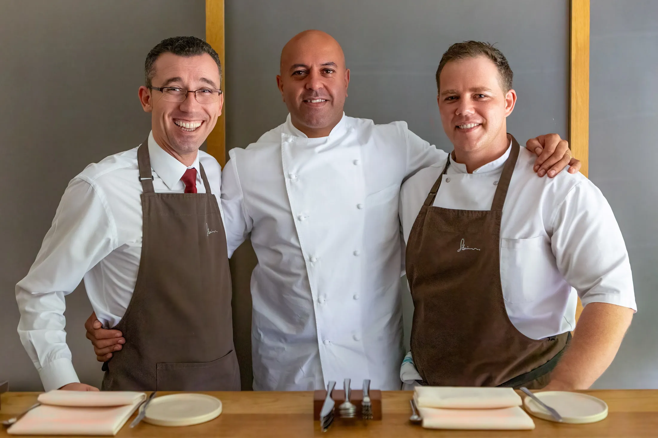 Sat Bains with his sommelier and head chef behind the wooden pass at Restaurant Sat Bains, Nottingham