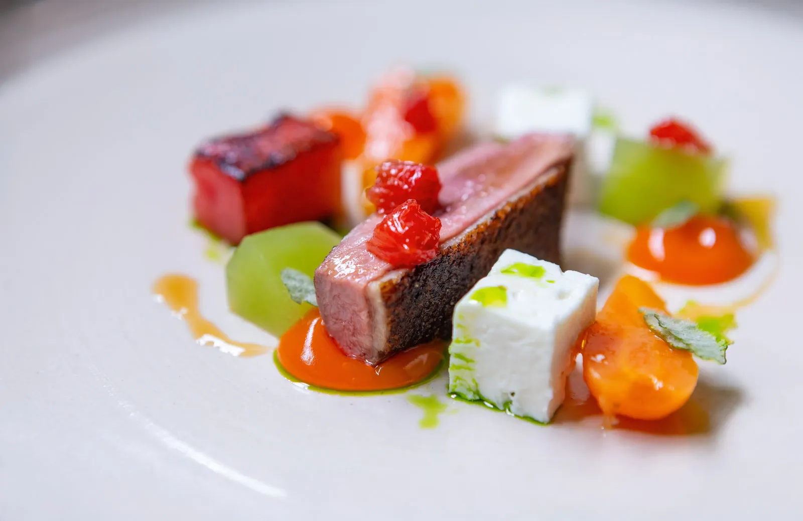 Tight macro shot of a meat course at Sat Bains, the precise arrangement of garnishes from the plated dish