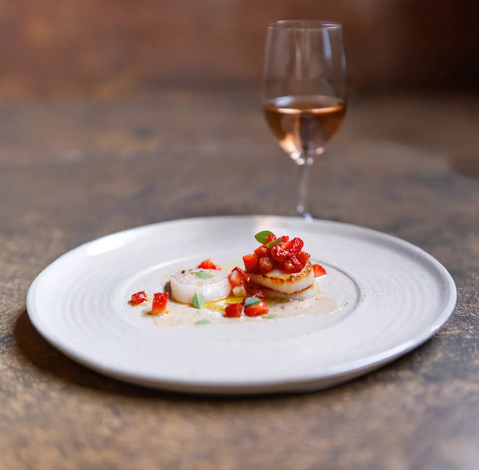 The scallop course with wine at Sat Bains, raw and seared scallop with strawberry salsa and light sauce, a blush wine glass out of focus behind